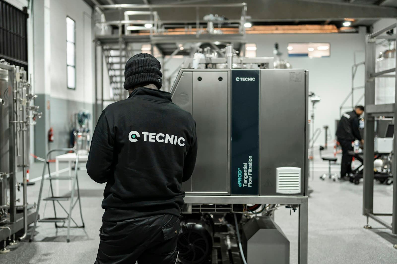 Technician inspecting stainless-steel process equipment in an industrial facility.