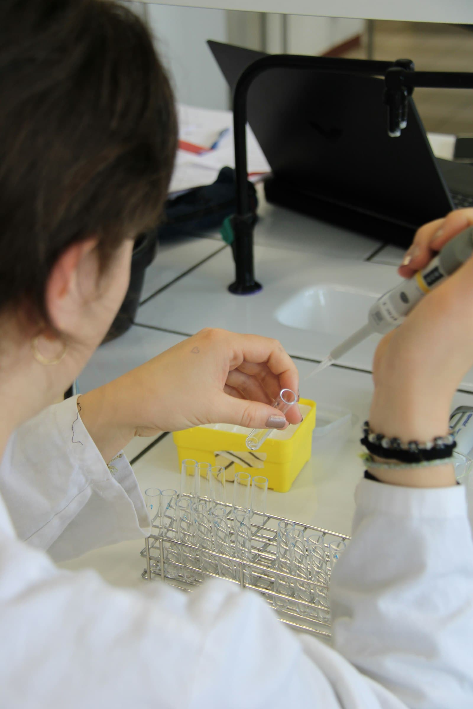 Laboratory technician handling a micropipette and sample tubes.